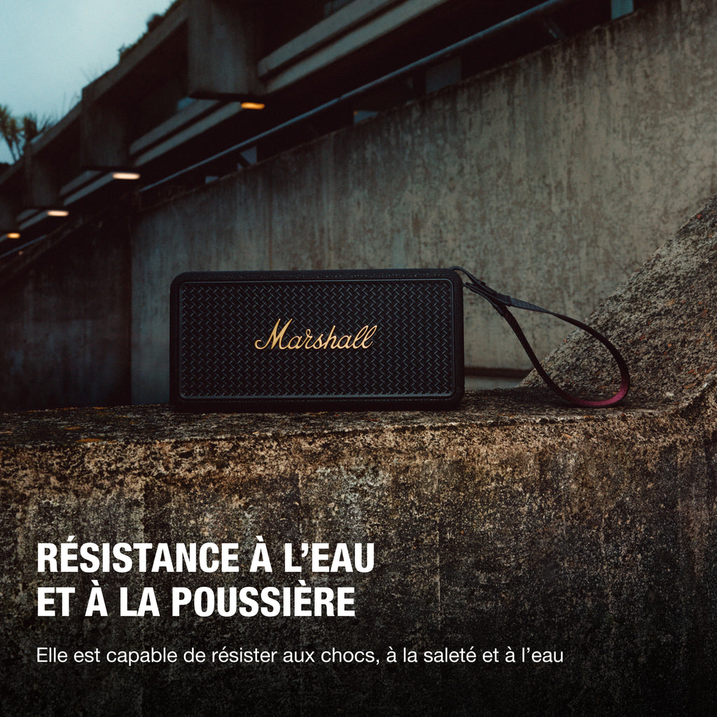 Marshall – Middleton II - Altavoz Portátil - Black & Brass, altavoz negro apoyado en un muro de piedra, con texto