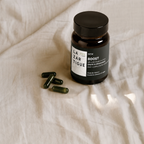 Lazartigue – Boost Gélules (Integratore Alimentare Anticaduta₁), flacone di integratori alimentari e alcune capsule verdi su un tessuto chiaro