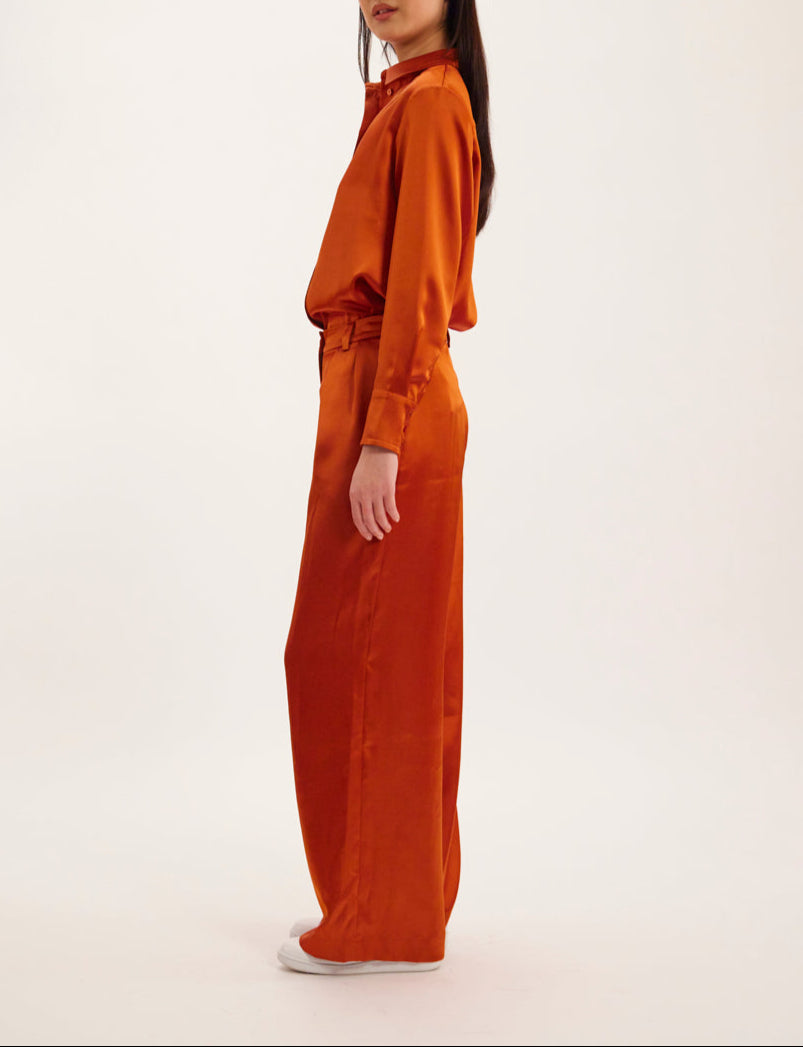 Ines De La Fressange – Luciano Trousers - Rust, model in profile wearing a matching rust satin shirt and trousers set