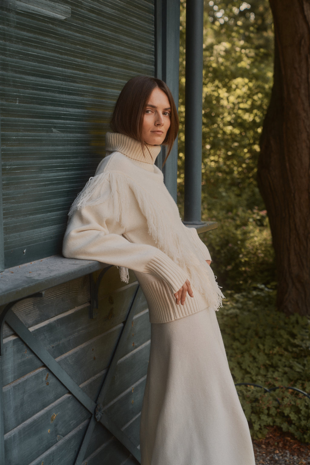 Michonet – Maglione Bergen White, modella che indossa un maglione a collo alto color panna e una gonna lunga coordinata