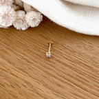 Instants Plaisirs – Piercing Oreille "Dani" Plaqué Or, un piercing doré avec un petit diamant, posé sur une table en bois