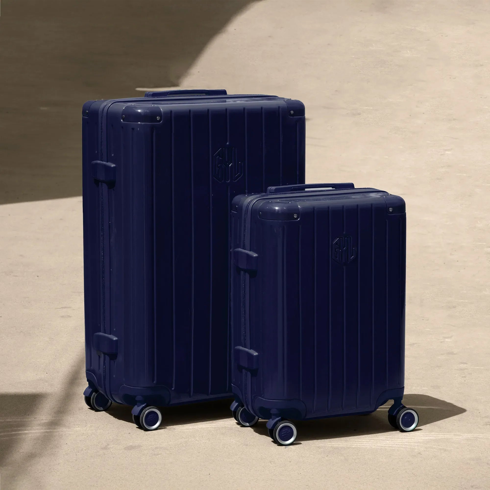 Set of two GYL Intemporelle navy rigid suitcases, cabin and hold sizes, placed on concrete floor. #navy_color