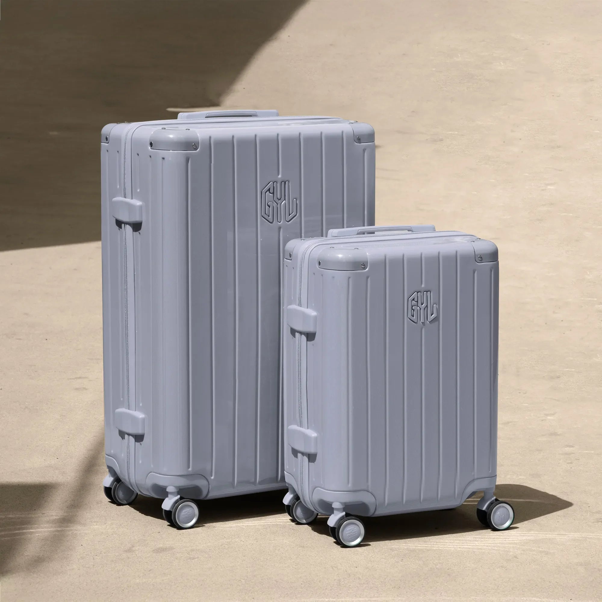 Set of two GYL Intemporelle silver rigid suitcases, cabin and hold sizes, placed on concrete floor. #silver_color