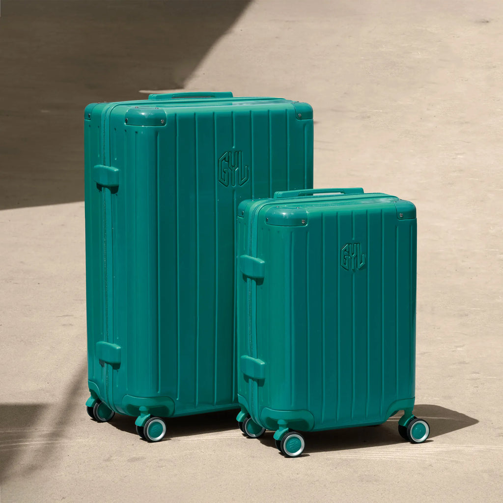 Set of two GYL Intemporelle water green rigid suitcases, cabin and hold sizes, placed on concrete floor. #color_green