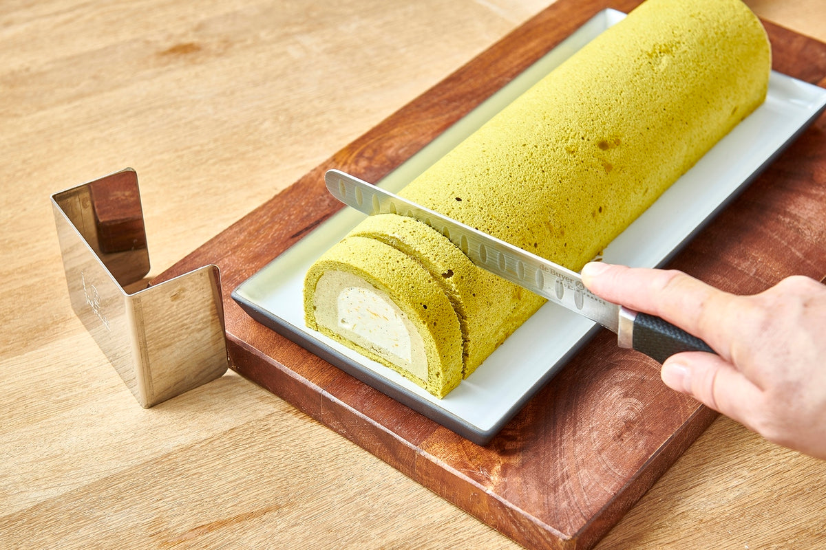 De Buyer – Gouttière À Bûche Ronde Démontable - Inox - Argent, une personne coupe un gâteau roulé vert sur une planche en bois