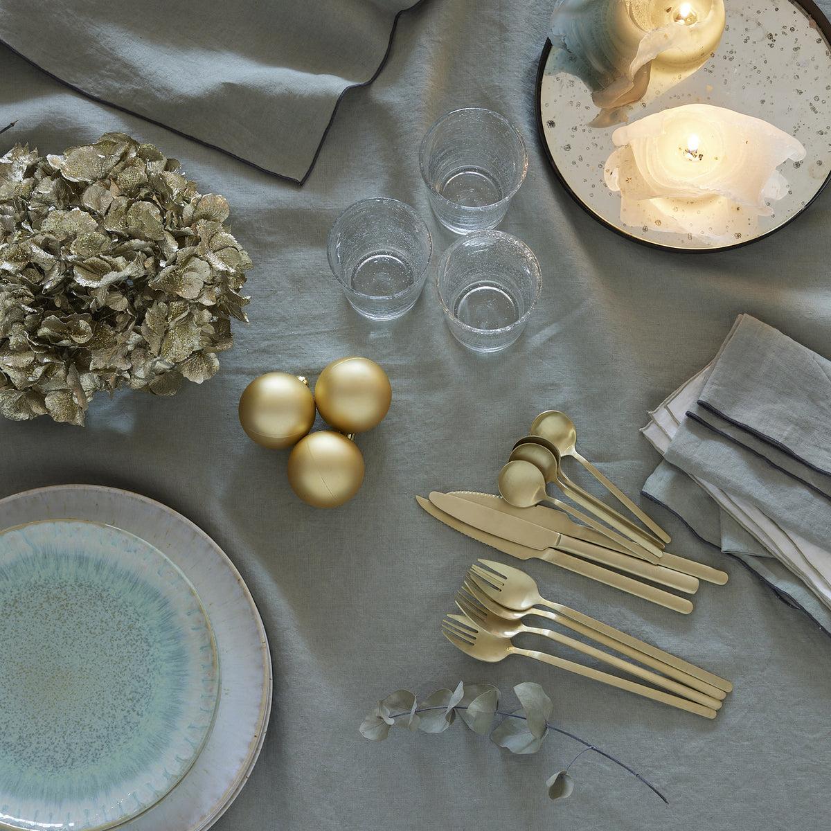 Blanc Cerise – Autour Du Lin - Nappe - Lin - Lichen Bourdon Anthracite, table dressée avec vaisselle, couverts dorés, boules de Noël et bougies