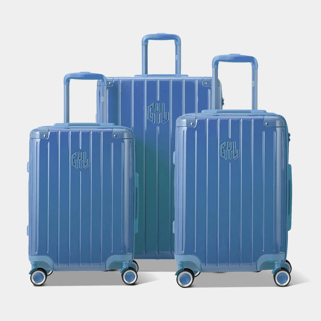 Trois valises rigides GYL Intemporelle bleu grisé, format cabine et soute, avec poignée trolley déployée.  #couleur_bleu grisé