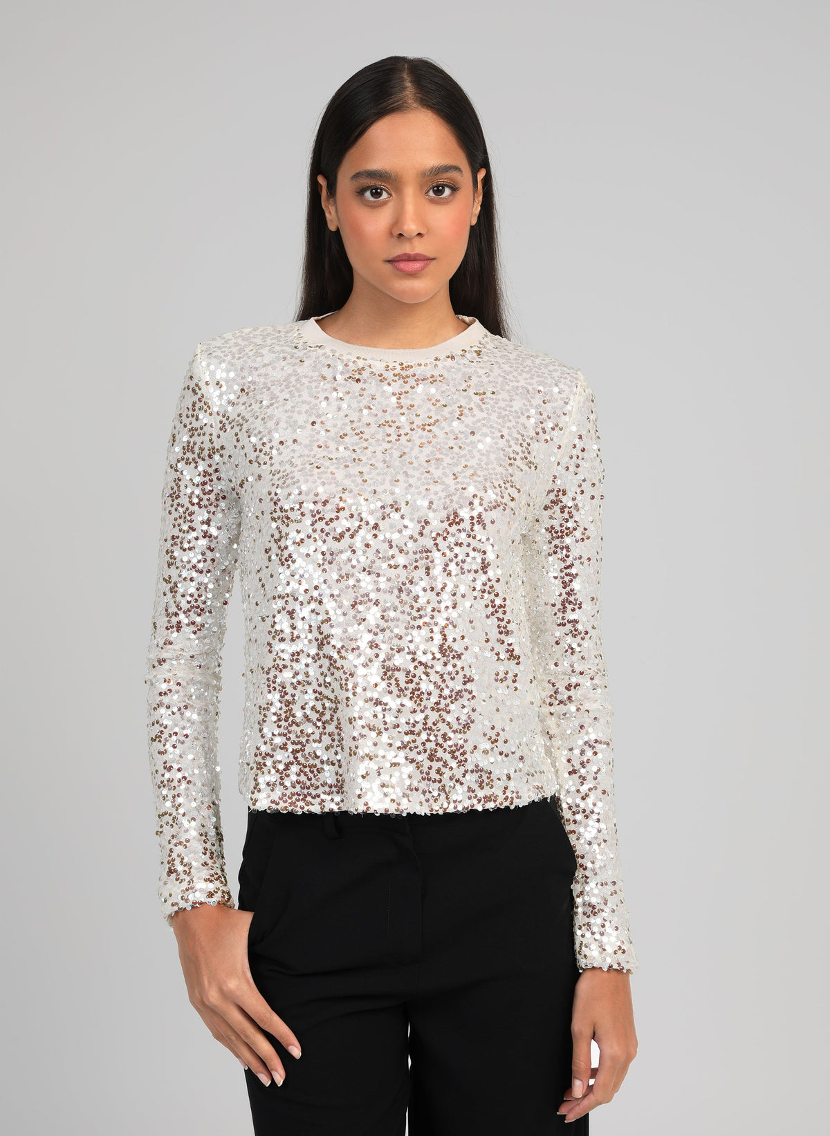 An'ge – T-Shirt Abela Ecru, mannequin portant un haut à manches longues à sequins argentés et pantalon noir