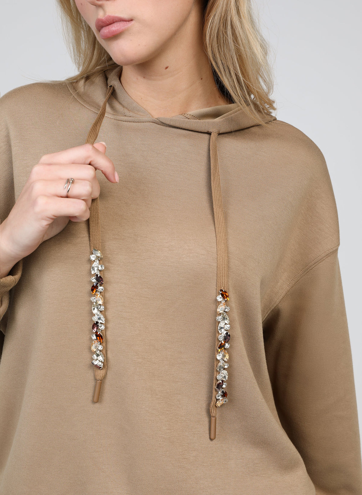 An'ge – Sweat Anika Camel, mannequin portant un sweat à capuche beige avec des cordons ornés de bijoux