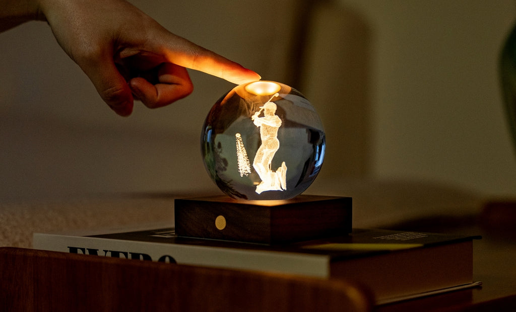 Gingko Design – Lampka Amber Crystal - Golf, dłoń dotykająca lampki nocnej w kształcie kryształowej kuli