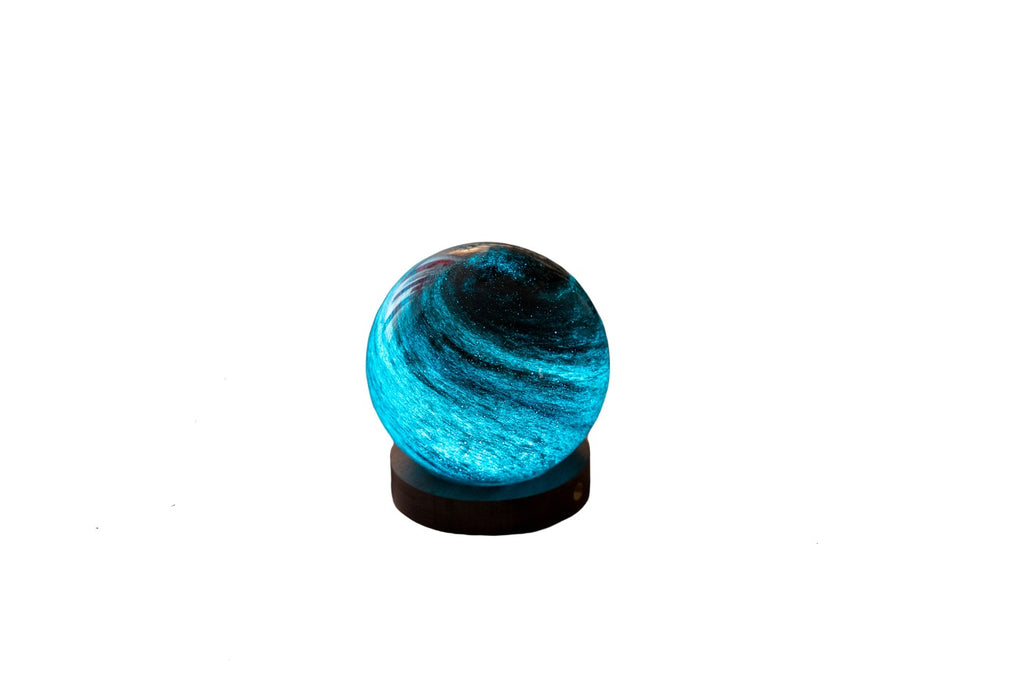 Gingko Design – Leuchte Astraglass - Stellar Ocean - 2 Größen, eine leuchtende blaue Glaskugel auf einem schwarzen Sockel