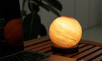 Gingko Design – Lampa Astraglass - Sand Storm - 2 rozmiary, kulista świecąca lampa stołowa stojąca na drewnianym stole