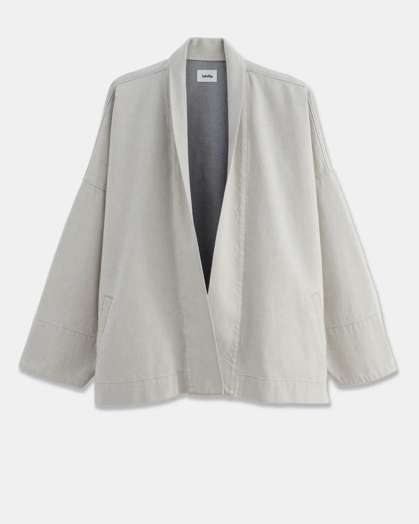 Veste ample en coton léger de couleur granit non teint, avec un col châle et des manches larges, parfaite pour une silhouette décontractée et confortable.