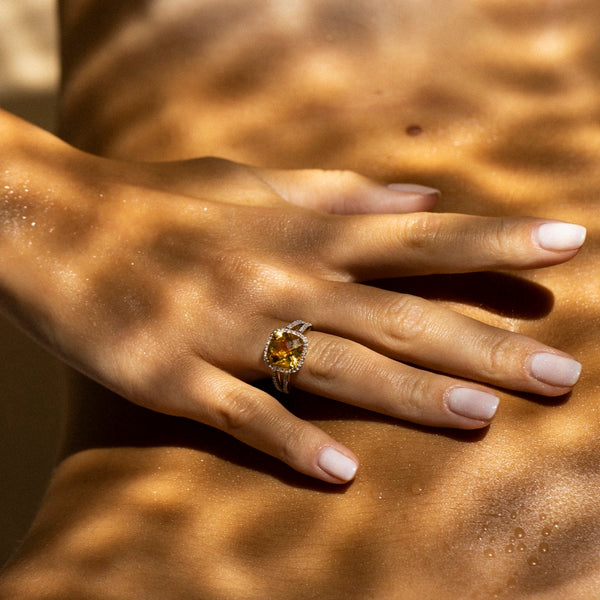 Diamanta – Ring "Divine Citrine 10" Diamant 0,10Ct/32 + Citrien 3,75/1, ring van goud en gele steen gedragen aan een zongebruinde hand