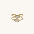 Instants Plaisirs – Bague "Neliora" Blanc Acier, bague dorée avec deux pierres ovales blanches, sur fond blanc uni