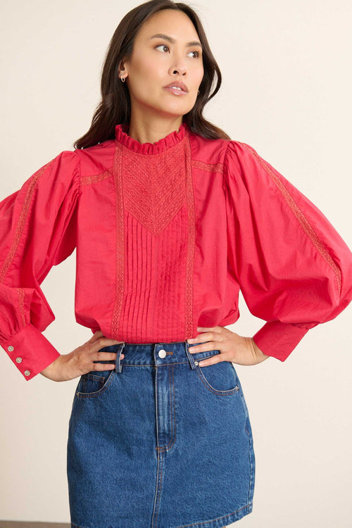 Manches longues légèrement bouffantes, poignets finis par un biais intérieur et plis discrets en tête de manche.