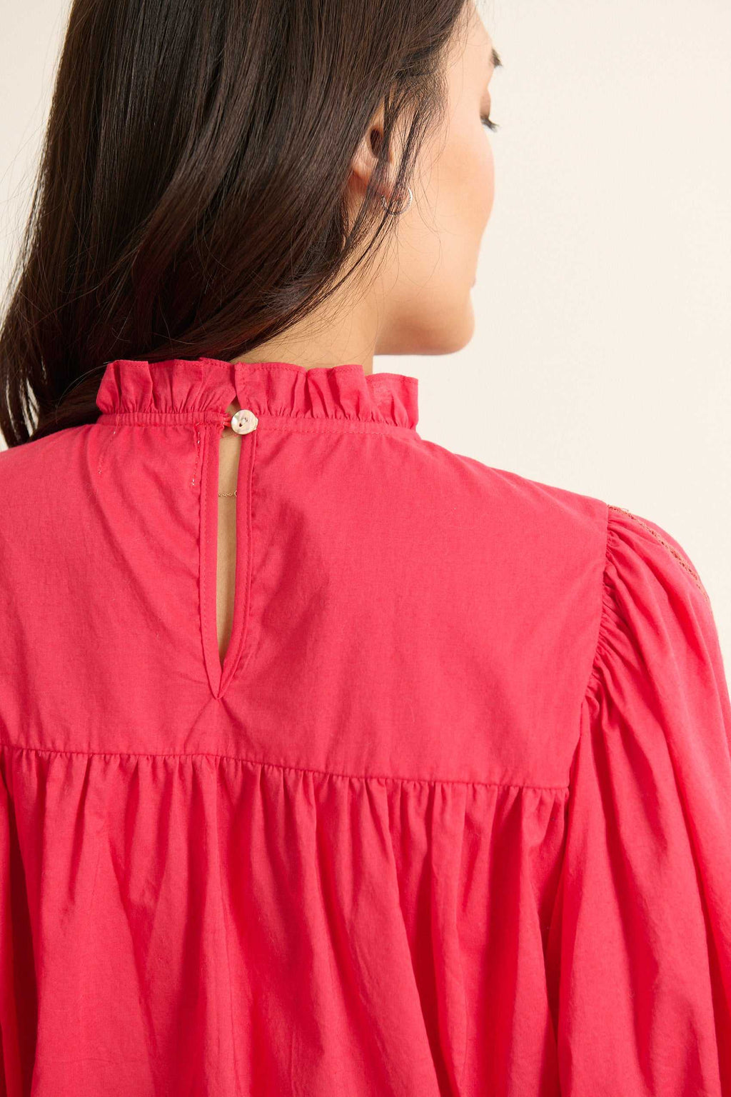 Vue arrière de la blouse ample, volume souple avec fronces sous l'empiècement et finition arrondie en bas.