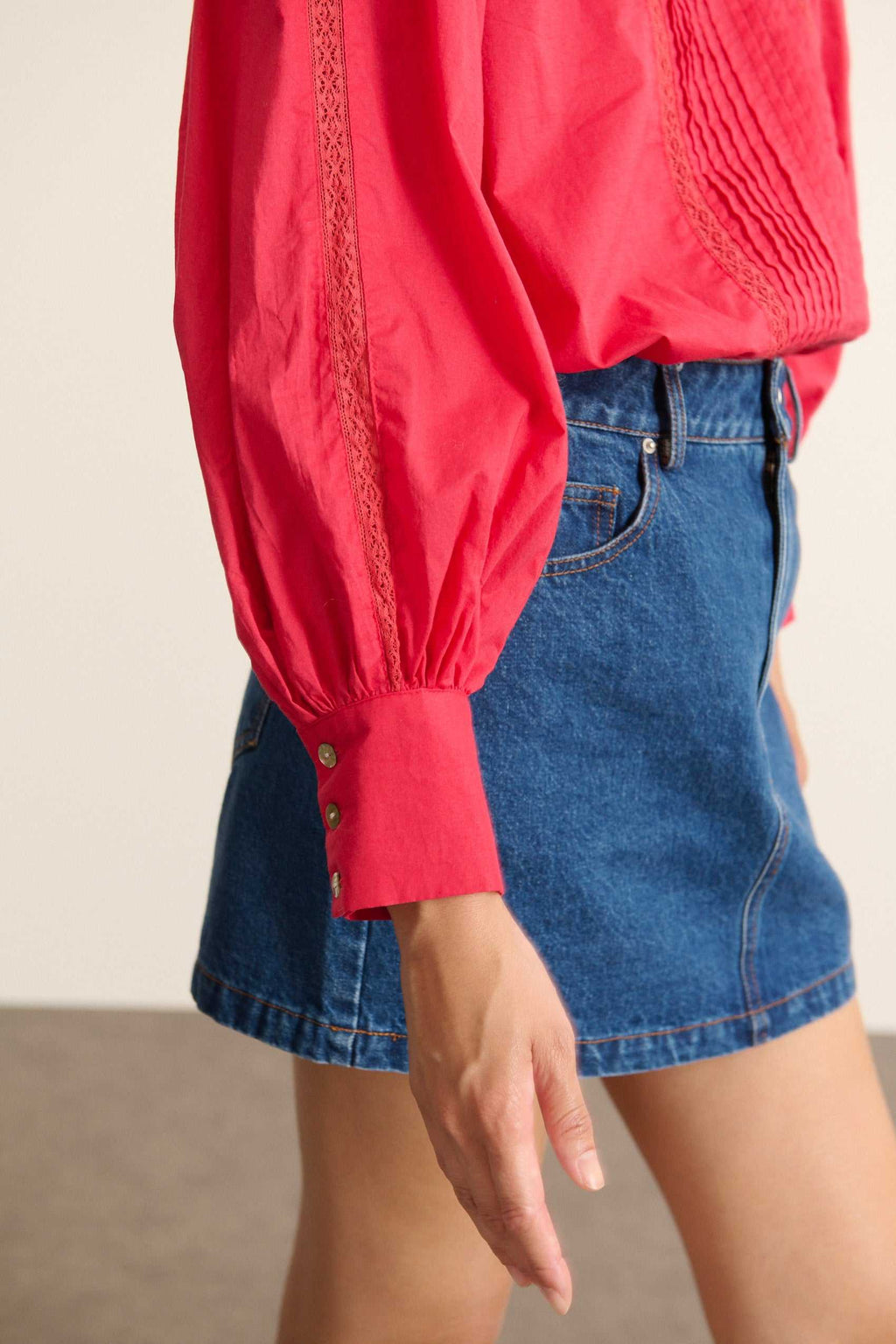 Femme portant la blouse BELLA coloris cerise, une blouse ample en voile de coton avec découpe composée de dentelle et plis.