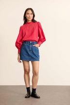 Mannequin femme de face portant une blouse ample cerise en voile de coton, col volanté et empiècements en dentelle.