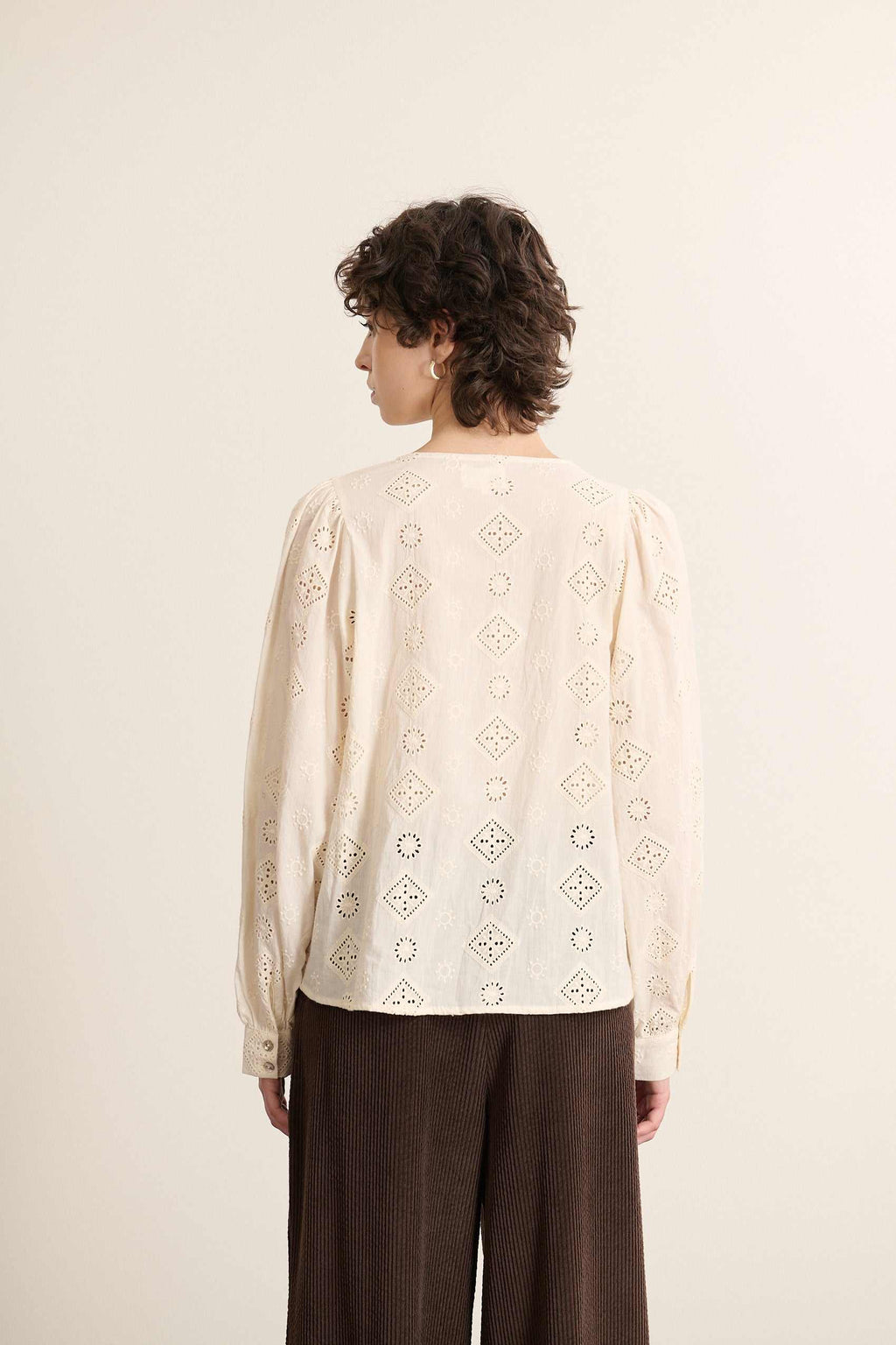 Col fendu sur le devant, fermé par un nœud, apparant une touche délicate à cette pièce en broderie anglaise écrue.