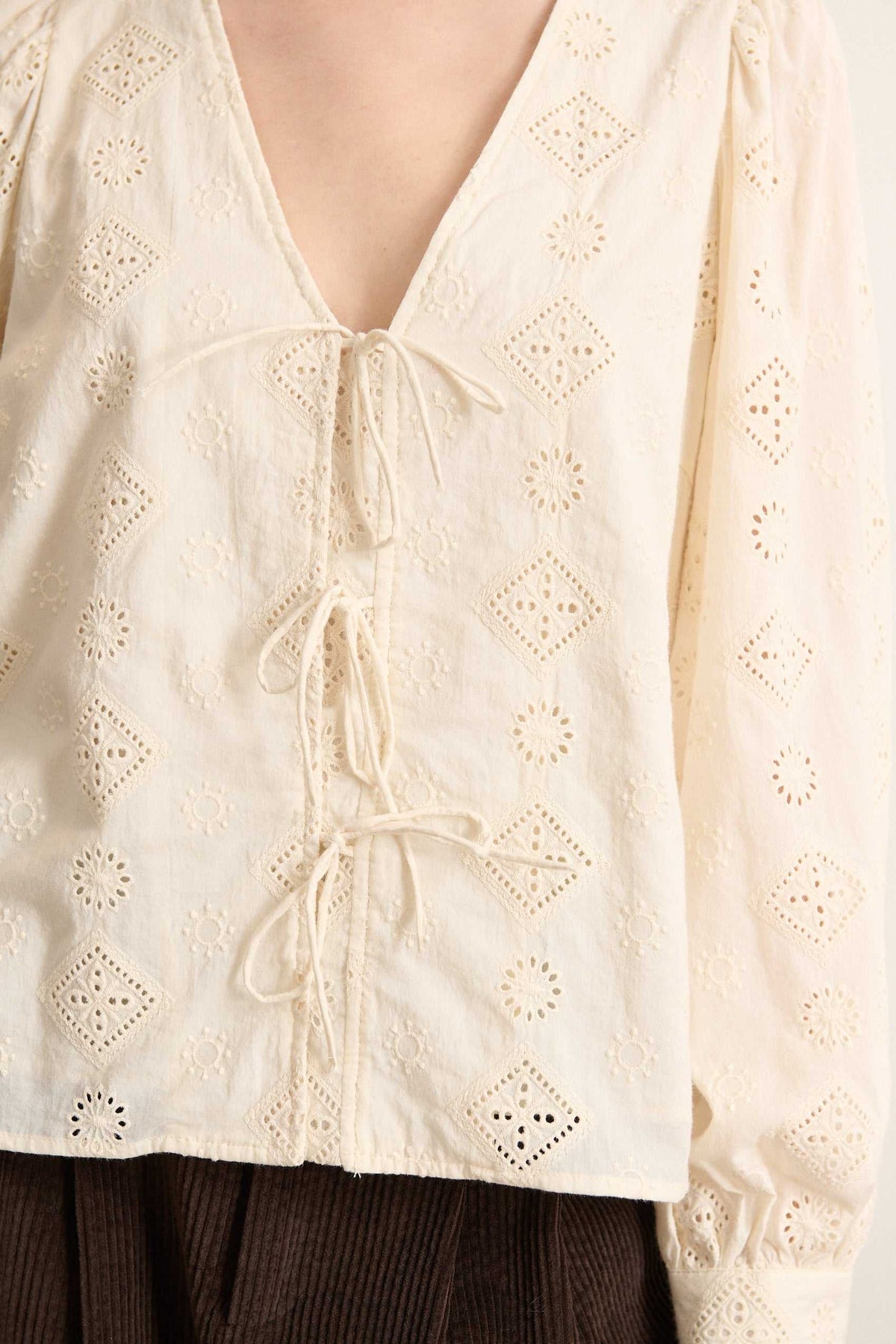 Tissu 100 % coton ajouré esprit broderie anglaise, motifs floraux brodés ton sur ton sur toute la surface de la blouse. 