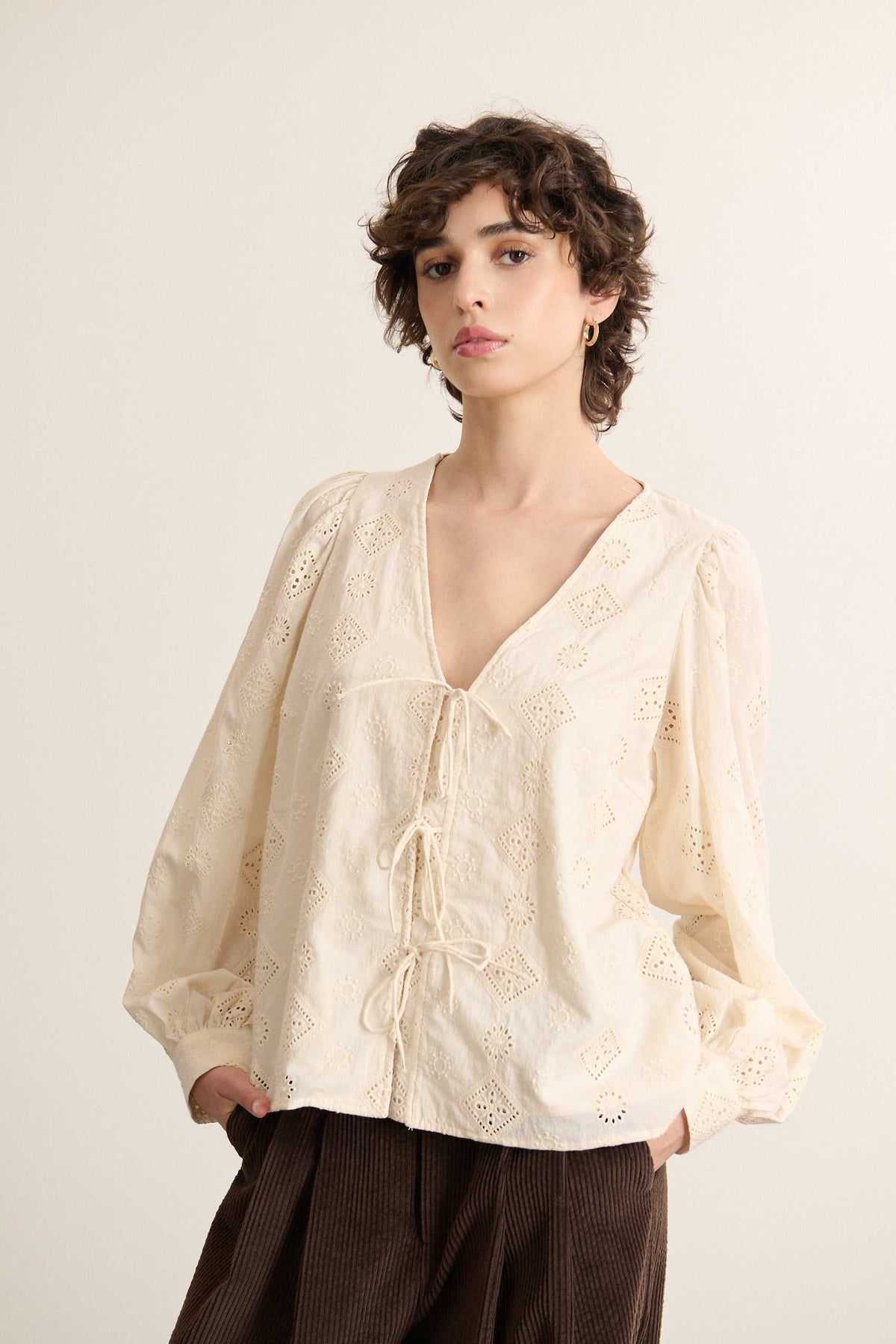 Mannequin femme de face portant une blouse écru en dentelle coton, coupe droite avec encolure dégagée. 