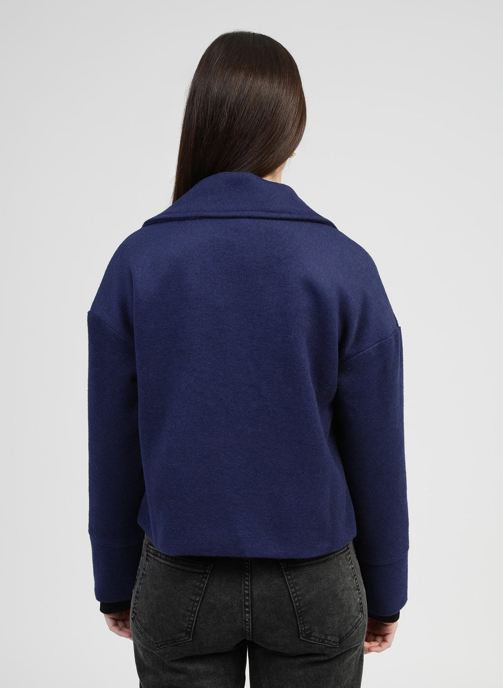 An'ge – Chaqueta Cassandra azul, mujer de espaldas con jersey azul marino de punto