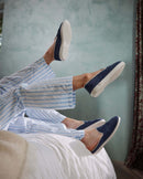 Zapatilla de mujer de piel azul denim sobre la cama Angarde