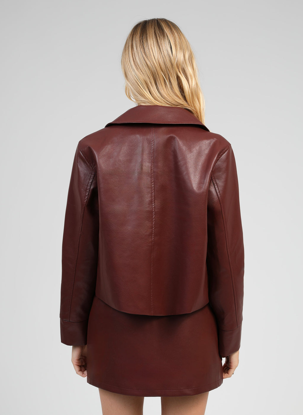 An'ge – Veste Claudiane Wine, mannequin de dos portant une veste et une jupe en cuir marron