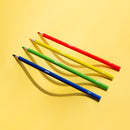 Crayons de couleur OMY étalés sur fond jaune – outils de dessin colorés pour enfants et adultes créatifs.