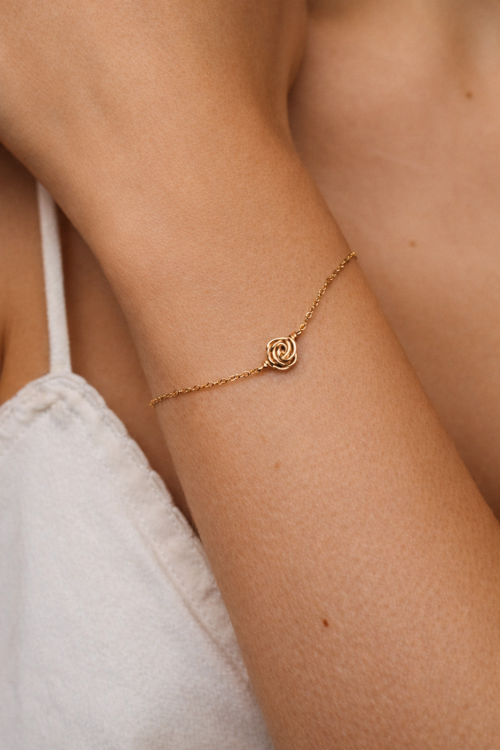 Pulsera Rosa puesta en la muñeca sobre una camiseta de tirantes clara