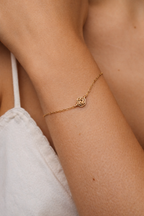 Pulsera Rosa puesta en la muñeca sobre una camiseta de tirantes clara