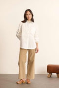 Mannequin femme de face portant une chemise ample blanche en coton, col classique, poche poitrine et coupe fluide. 