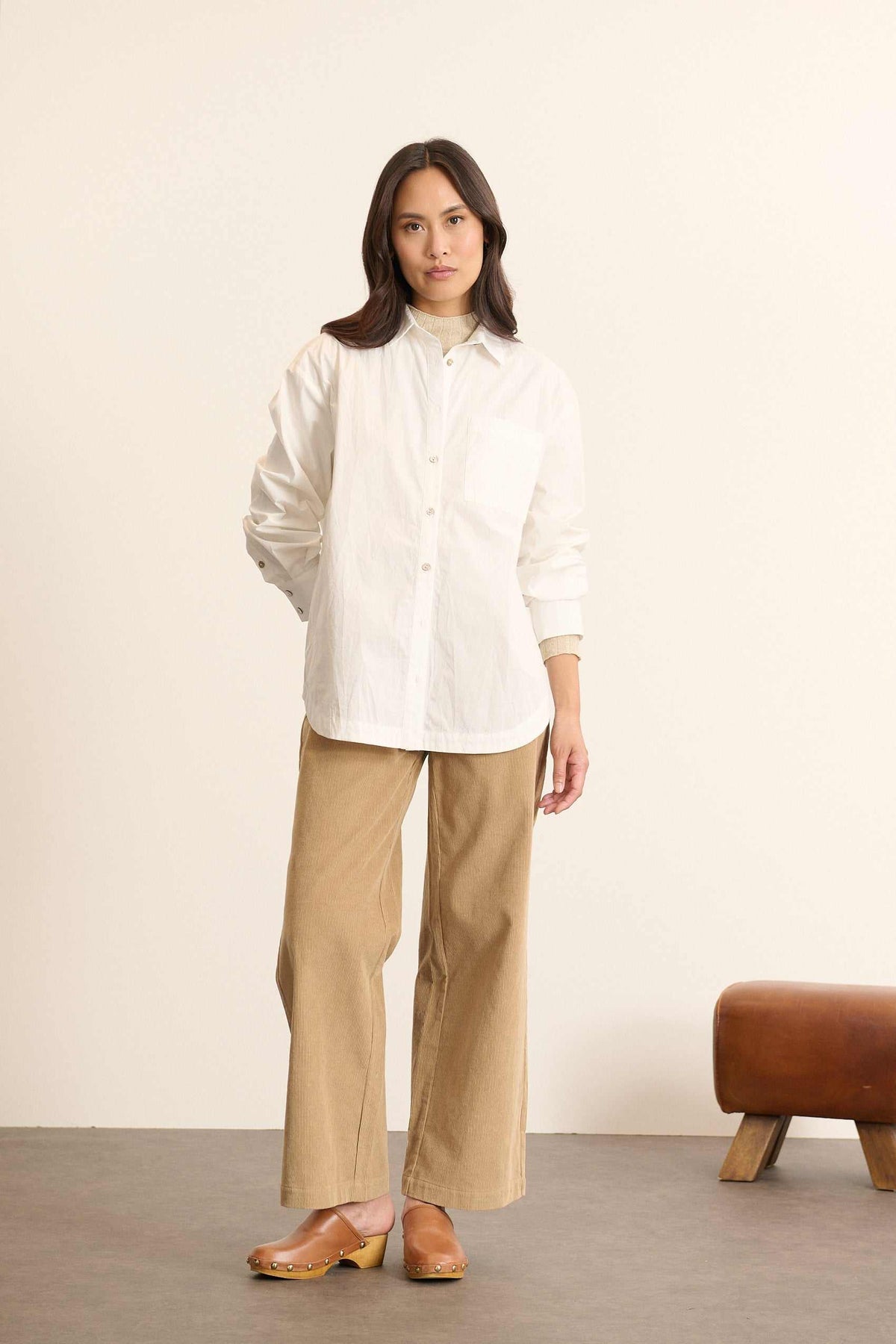 Mannequin femme de face portant une chemise ample blanche en coton, col classique, poche poitrine et coupe fluide. 