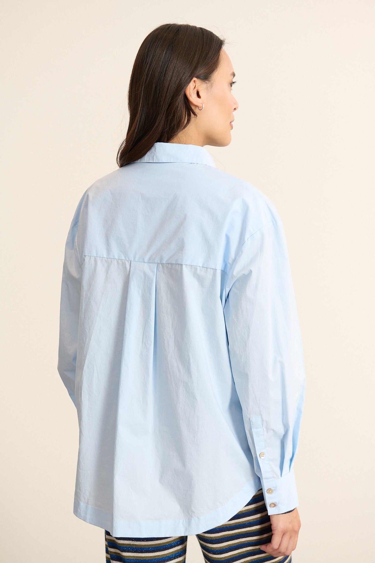 Vue arrière de la chemise ample, découpe horizontale haute avec fronces légères pour créer du volume au dos. 