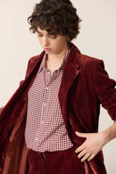 Fermeture boutonnée sur patte centrale avec petits boutons plats cousus sur le devant, col classique. 