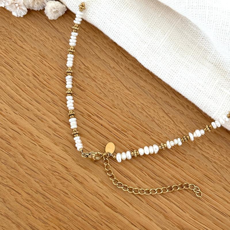 Instants Plaisirs – Collier "Emilie" Acier, collier de perles blanches et dorées sur une table en bois clair