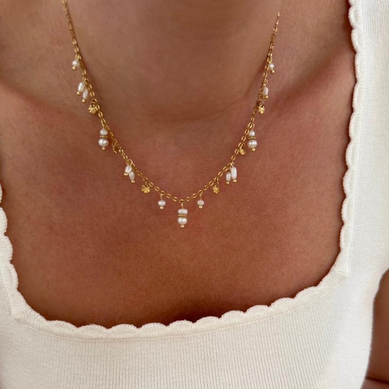 Instants Plaisirs – Collier "Adeline" Acier, collier doré avec perles blanches porté sur un décolleté blanc