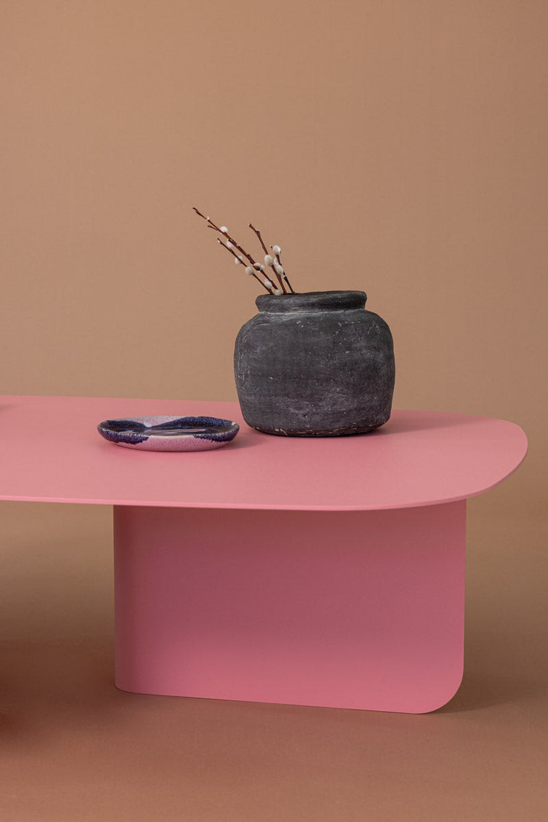 Moderne Couchtisch Livia in Pink mit dekorativem Topf und Teller auf einer neutralen Hintergrundfarbe.