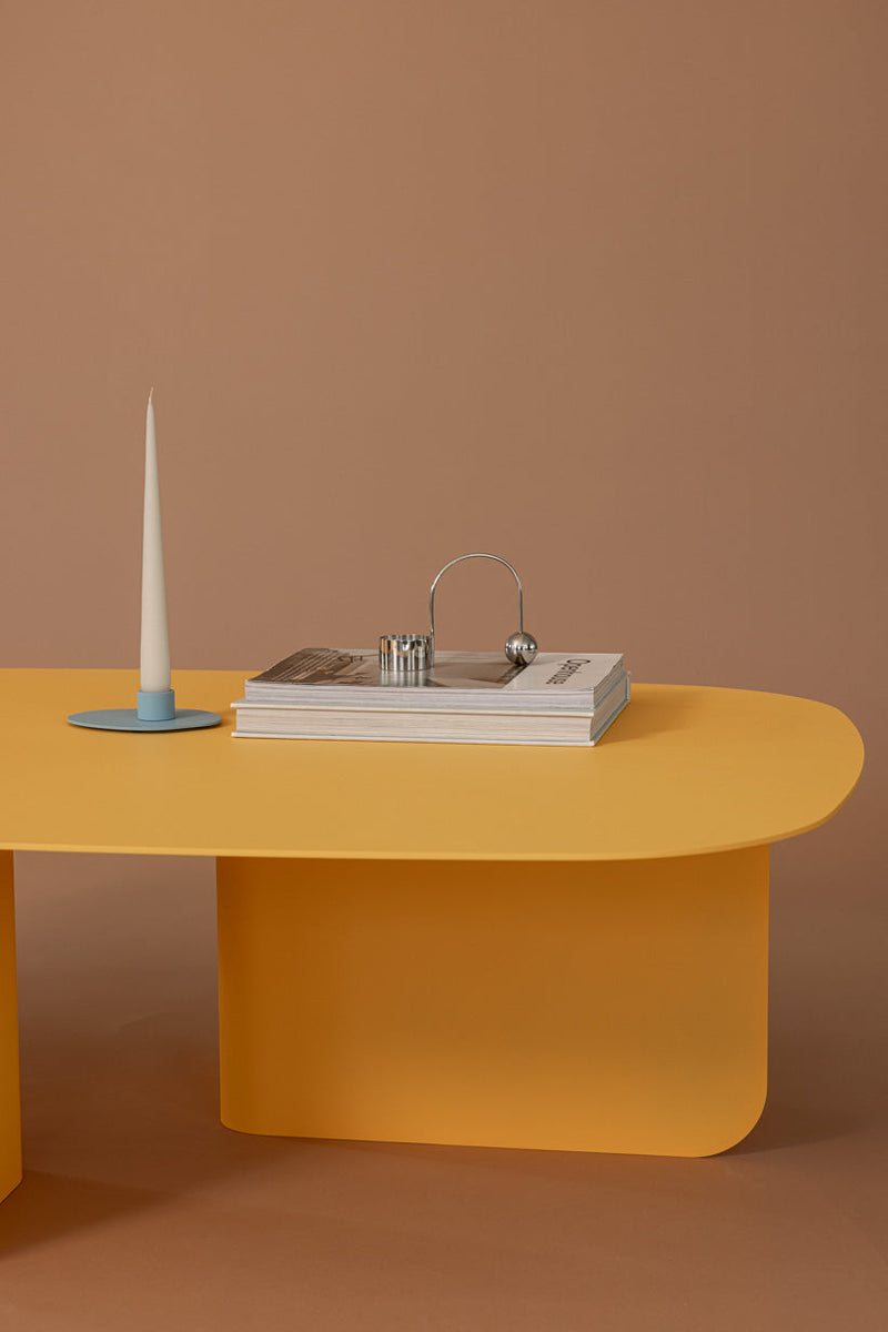 Moderne Couchtisch Livia in Gelb mit Kerze und dekorativen Zeitschriften.