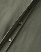 Tissu popeline en coton kaki avec boutonnières noires sobres, montrant la qualité et la finesse de la matière idéale pour un pantalon léger et élégant.