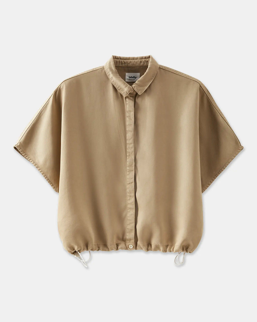 Chemise femme beige en tissu fluide avec coupe ample, col classique et bas resserré par un cordon ajustable.