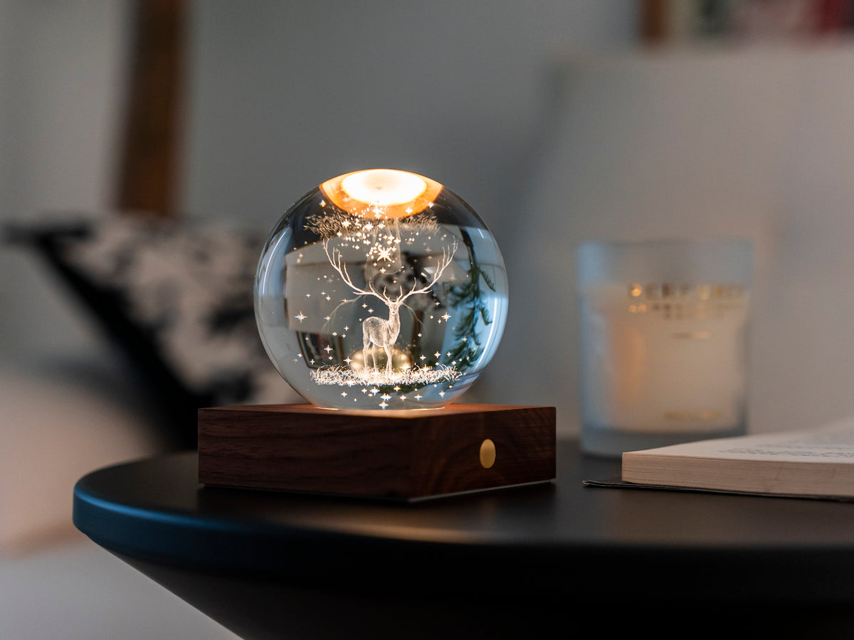 Gingko Design – Amber Crystal Leuchte - Hirsch, eine leuchtende Glaskugel mit einem Hirsch auf einem Nachttisch