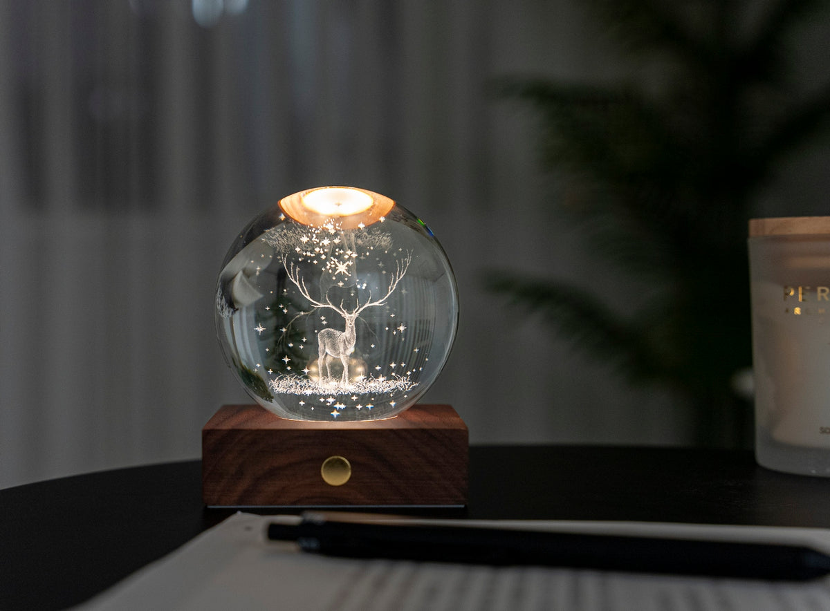 Gingko Design – Bernstein-Kristall-Licht – Hirsch, eine leuchtende Glaskugel mit einem Hirsch im Inneren auf einem Tisch