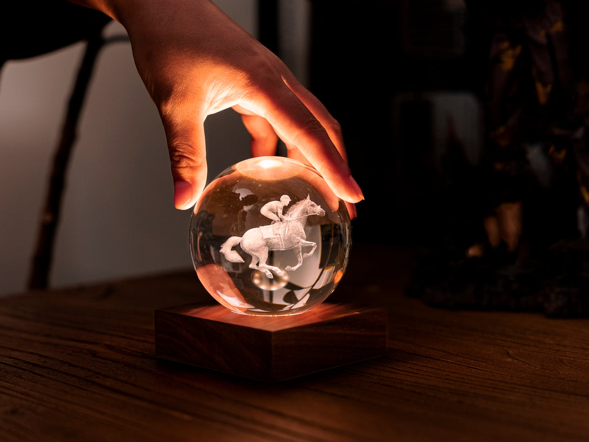Gingko Design – Bernstein-Kristall-Licht – Pferderennen, Hand auf einer leuchtenden Kristallkugel mit eingraviertem Pferd