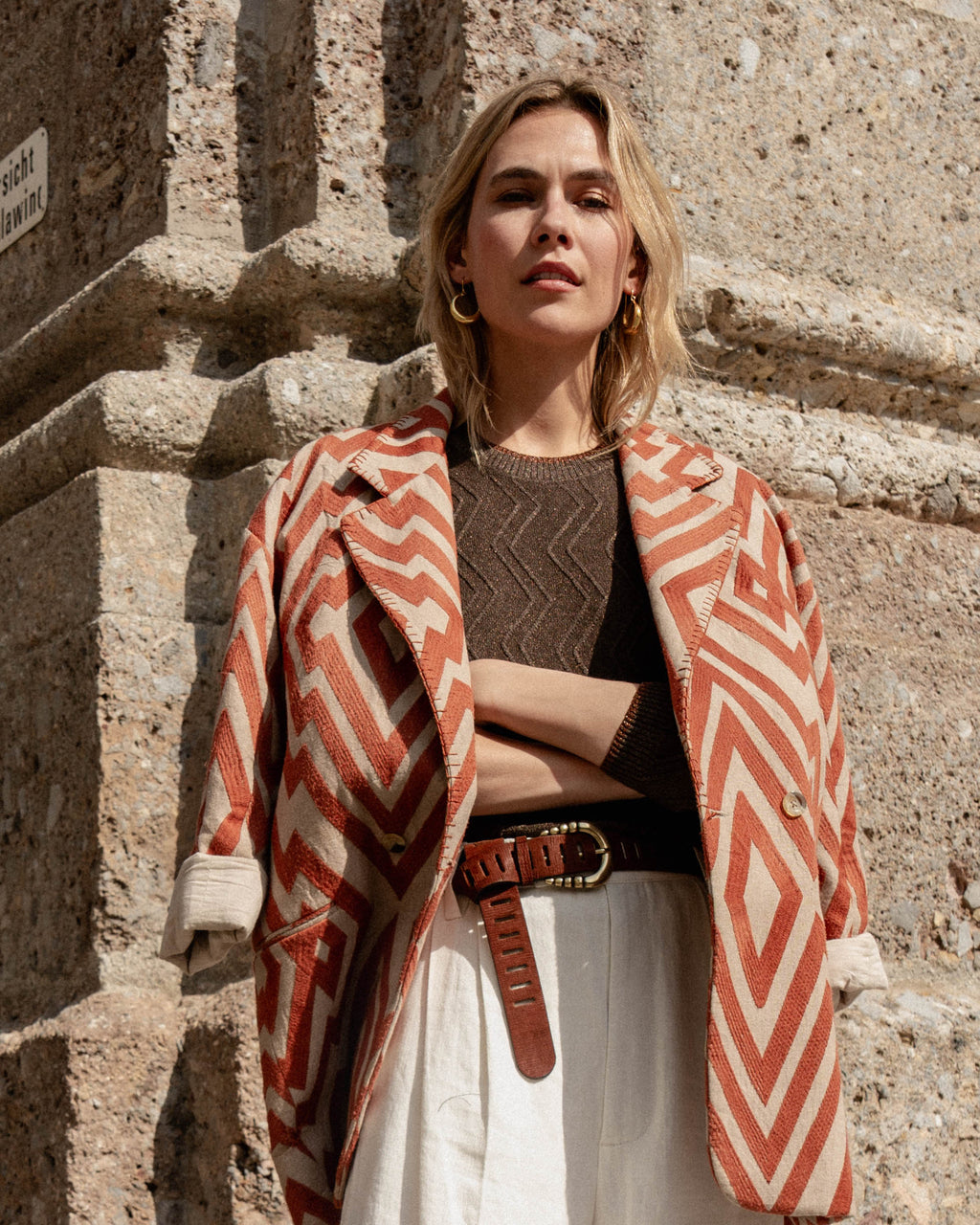 Michonet – Manteau Chevron, modella bionda che indossa una giacca a motivi geometrici e pantaloni chiari