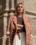 Michonet – Manteau Chevron, modella bionda che indossa una giacca a motivi geometrici e pantaloni chiari