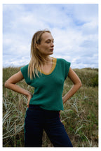 Michonet – Ärmlös Väst Knitted Green, blond kvinnlig modell iklädd grön tröja och blå byxor