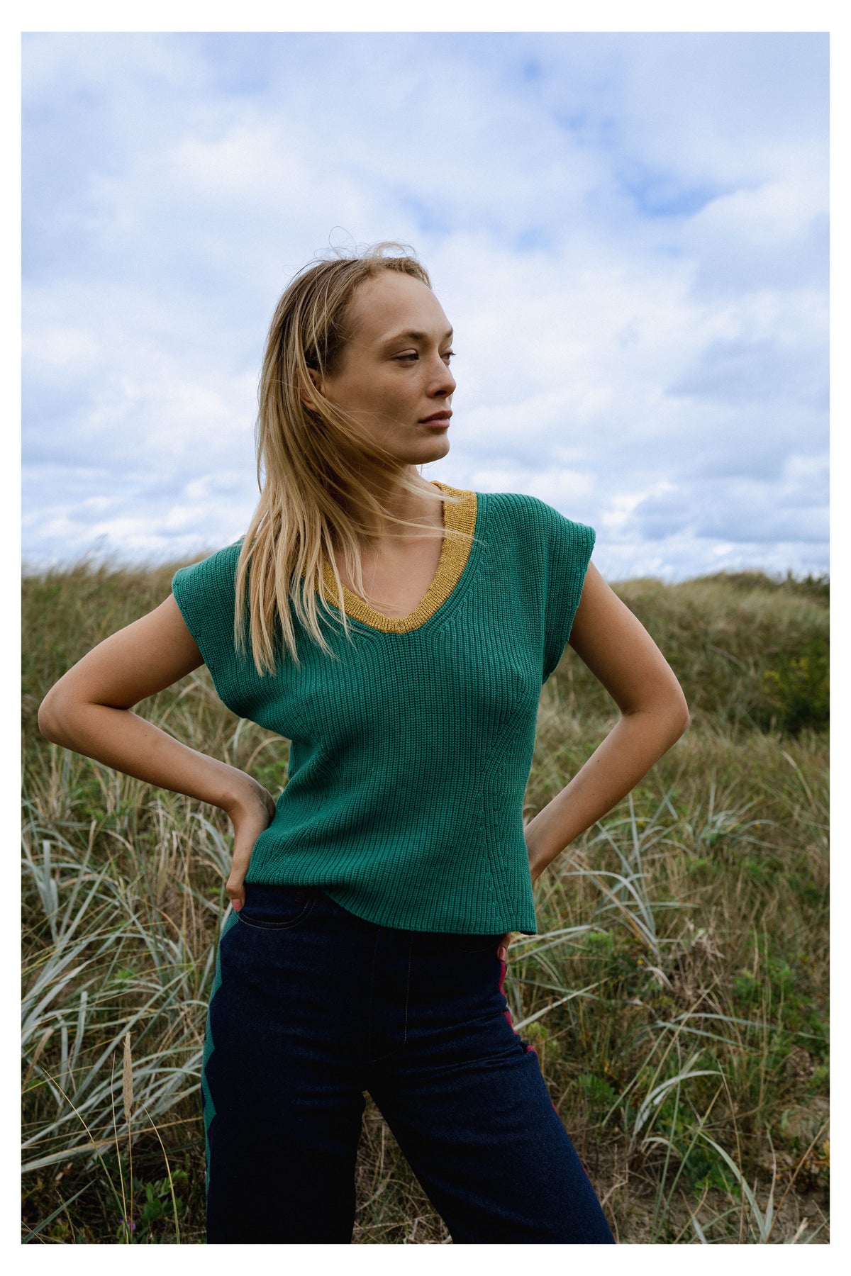 Michonet – Ärmlös Väst Knitted Green, blond kvinnlig modell iklädd grön tröja och blå byxor