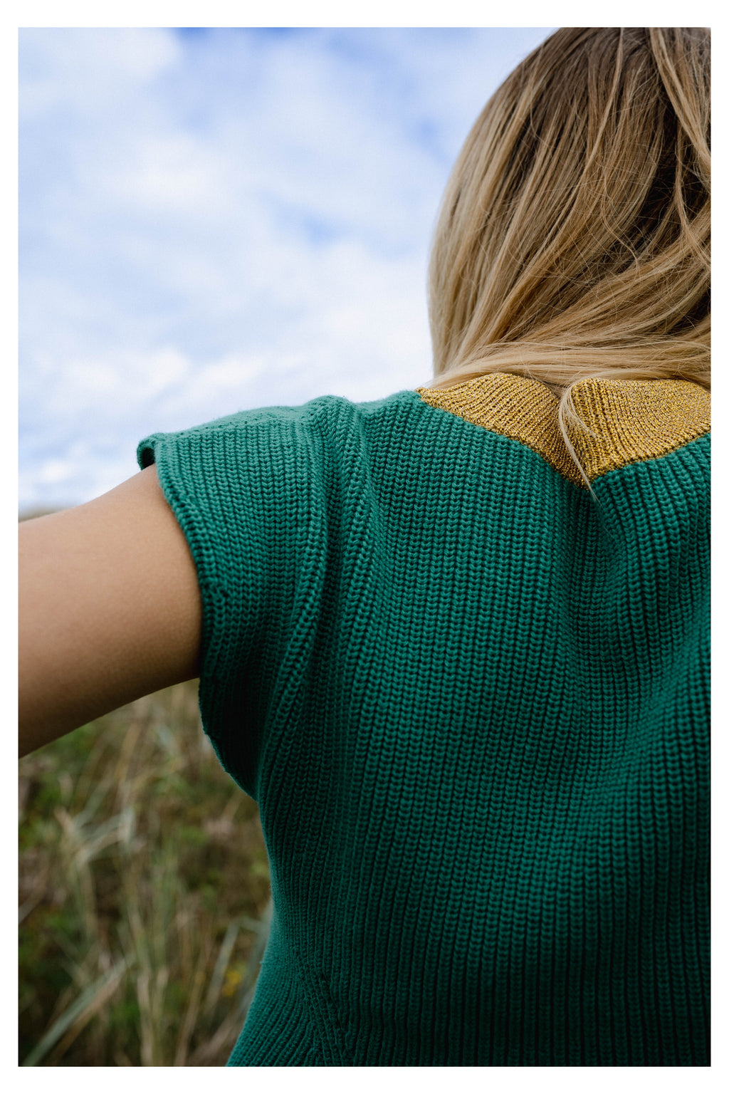 Michonet – Ärmlös Väst Knitted Green, kvinna sedd bakifrån iklädd grön- och gulstickad tröja